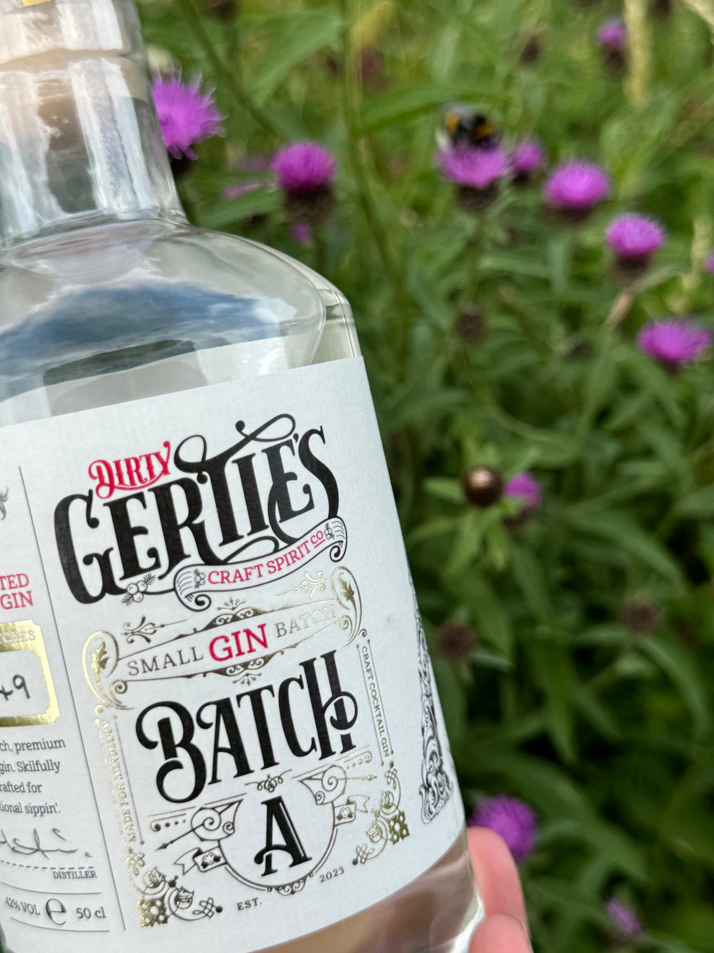 picture of a gin bottle with purple flowers in the background