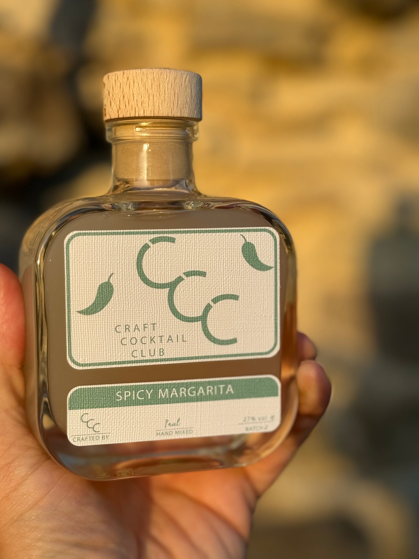 picture of a spicy Margarita craft cocktail club bottle being held up as the sun sets