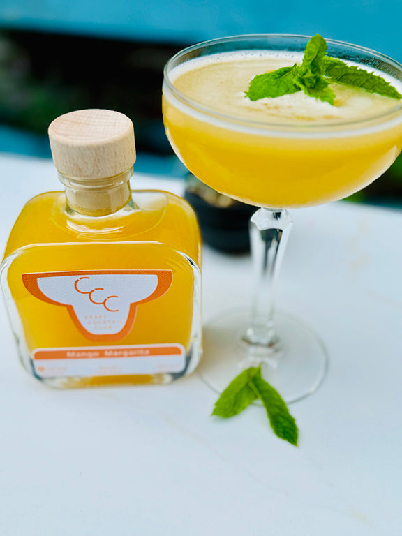 picture of a mango margarita taken outside with mint leaves in the top 