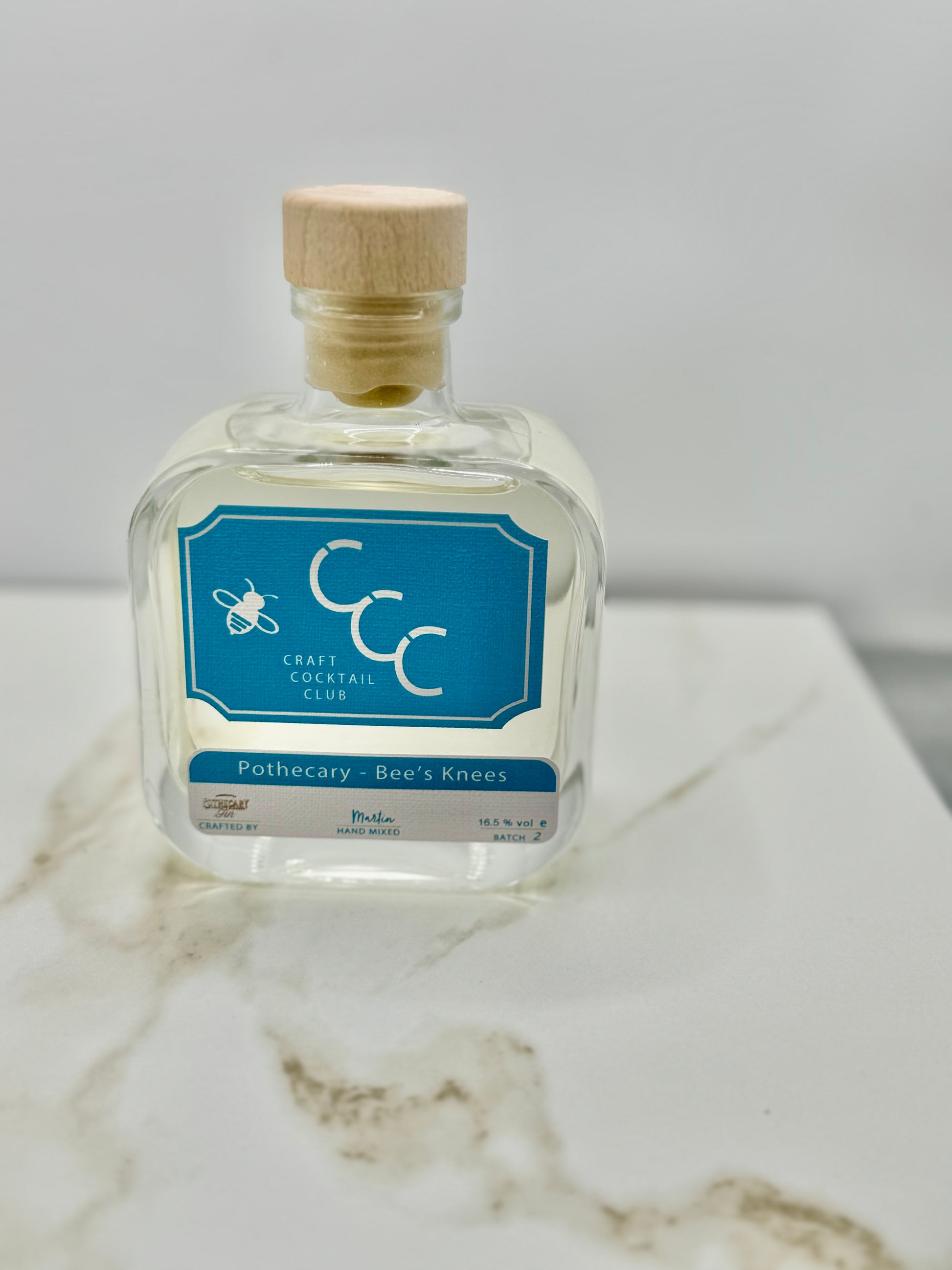 picture of a single bottle of bees knees cocktail. blue label clear liquid 