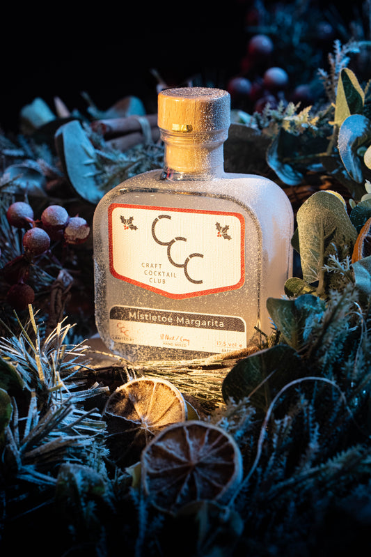 Bottle of Mistletoe Margarita cocktail surrounded by festive decorations