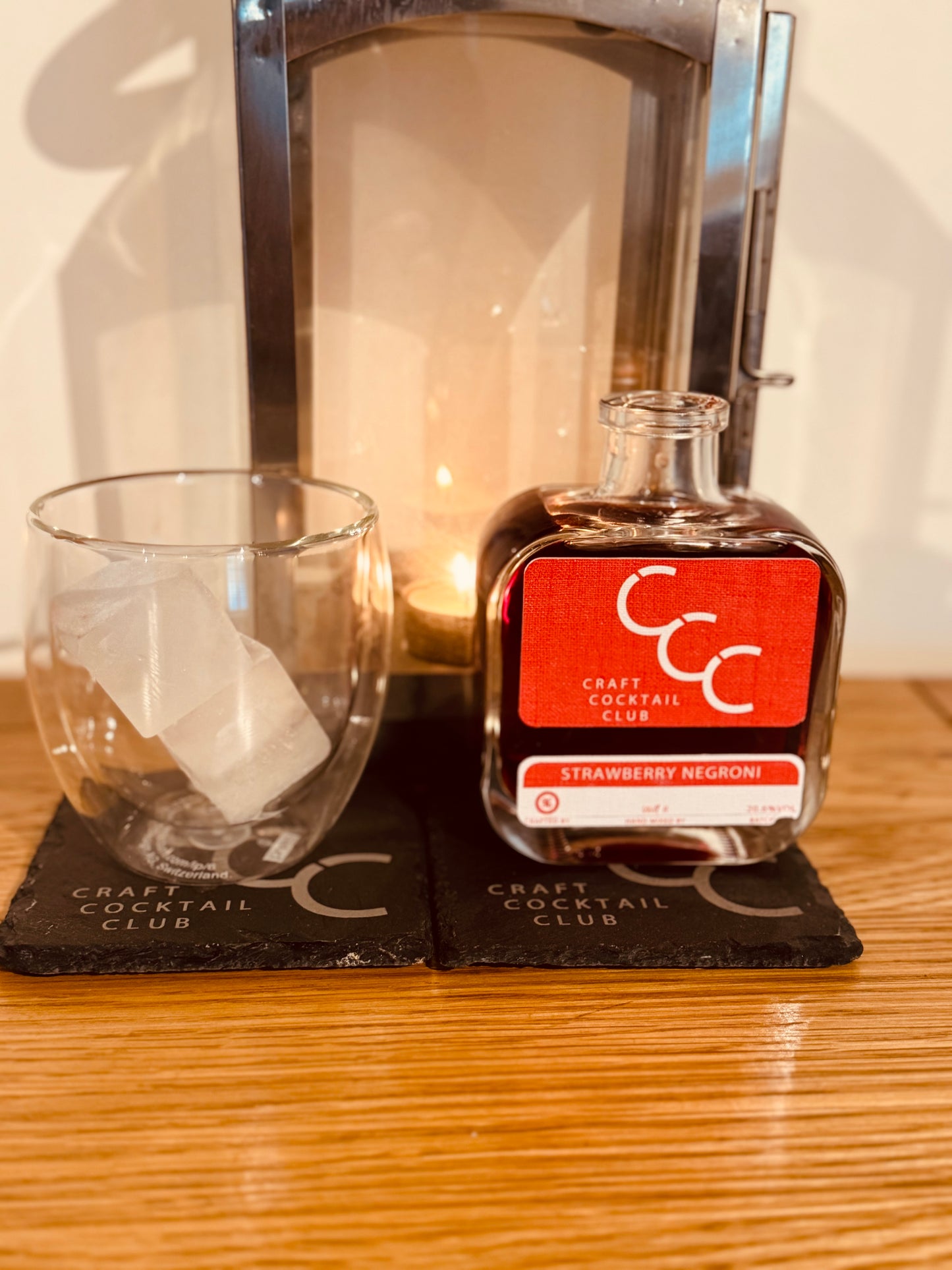 picture of a customers glass and strawberry negroni next to a lantern 