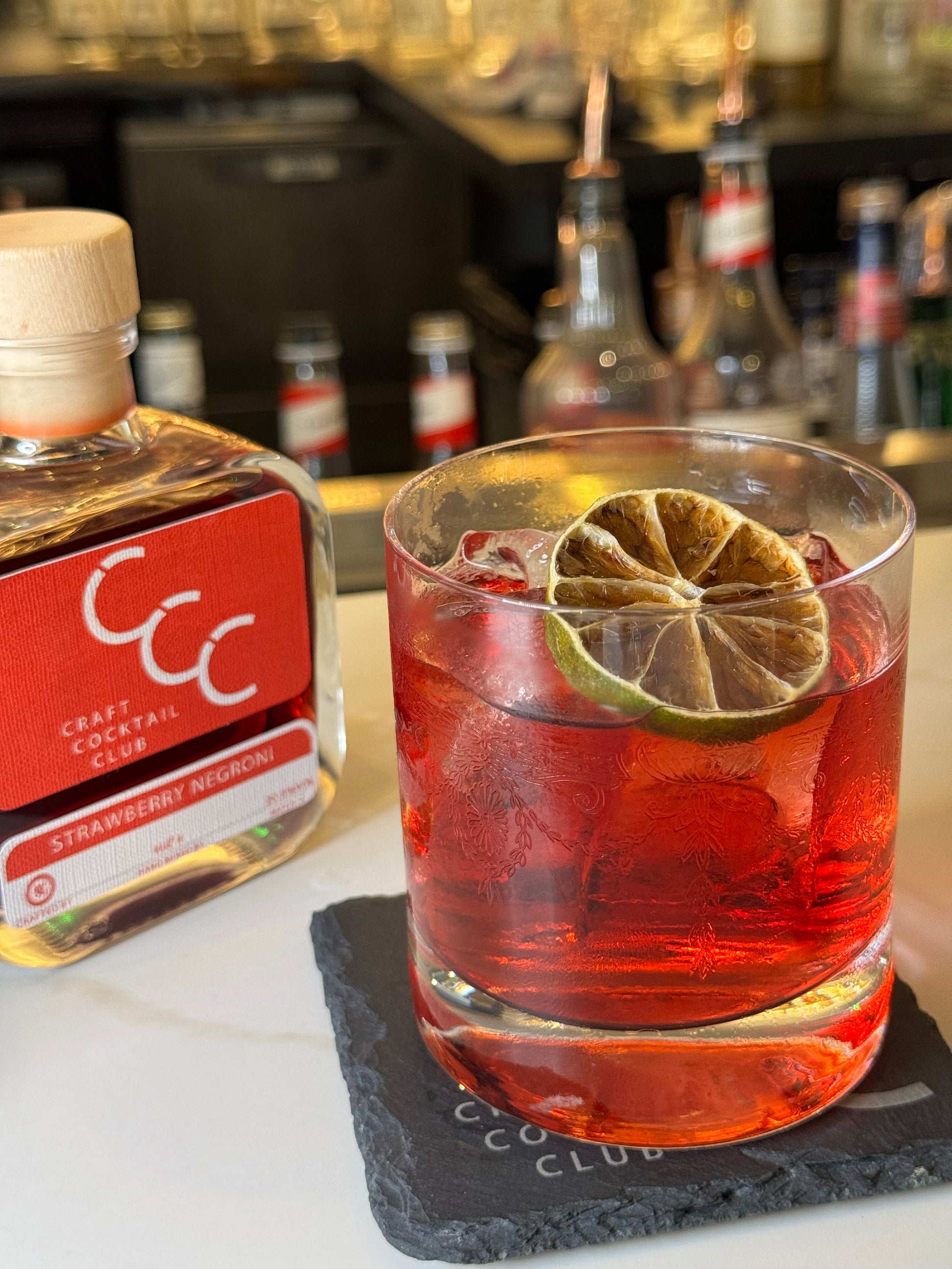 picture of a negroni on a bar with a bottle of negroni next to it