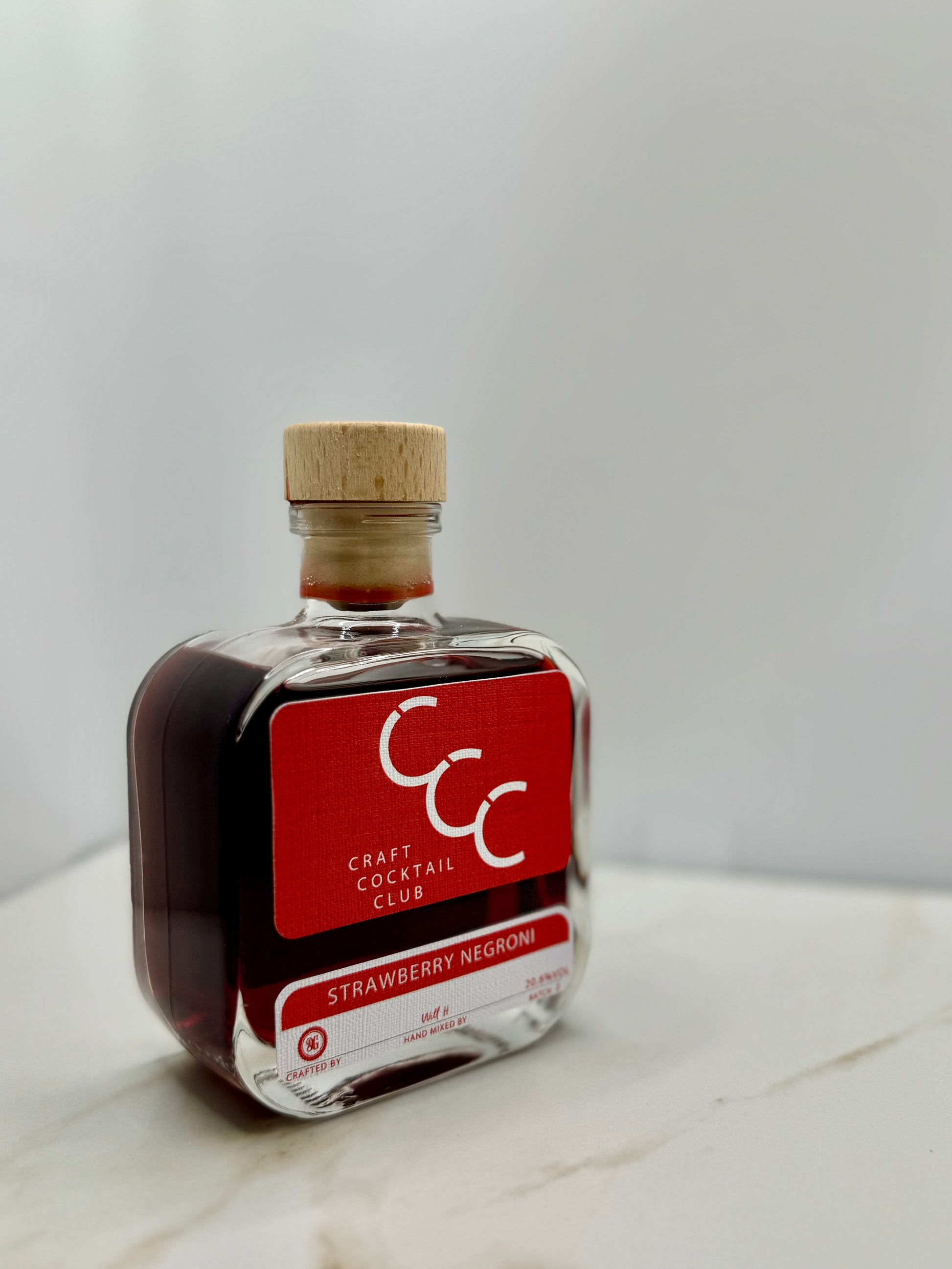 picture of a single bottle of strawberry negroni on a cream tile 