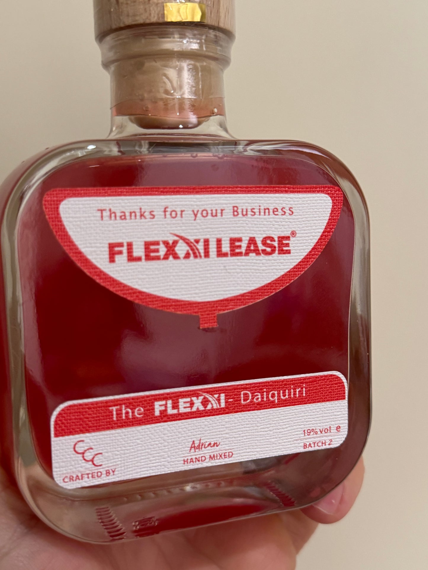 Corporate gift drinks Bottle with Flexi Lease label held by a hand against a neutral background