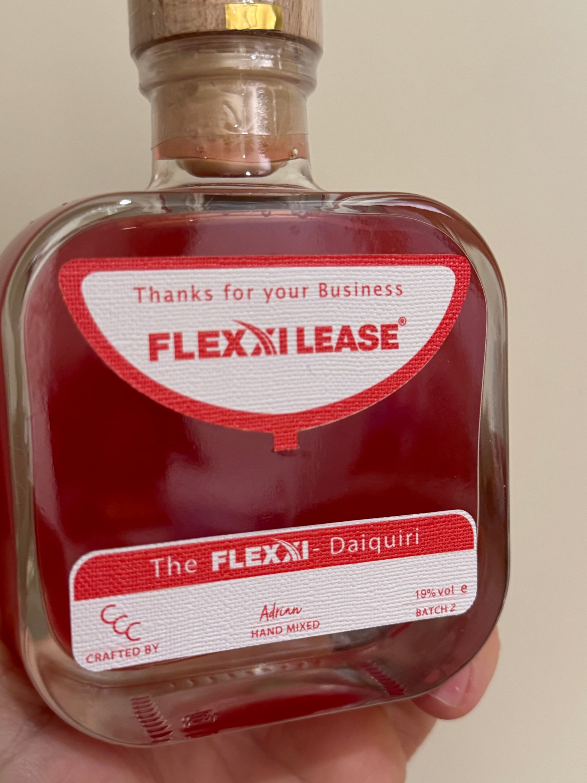Corporate gift drinks Bottle with Flexi Lease label held by a hand against a neutral background